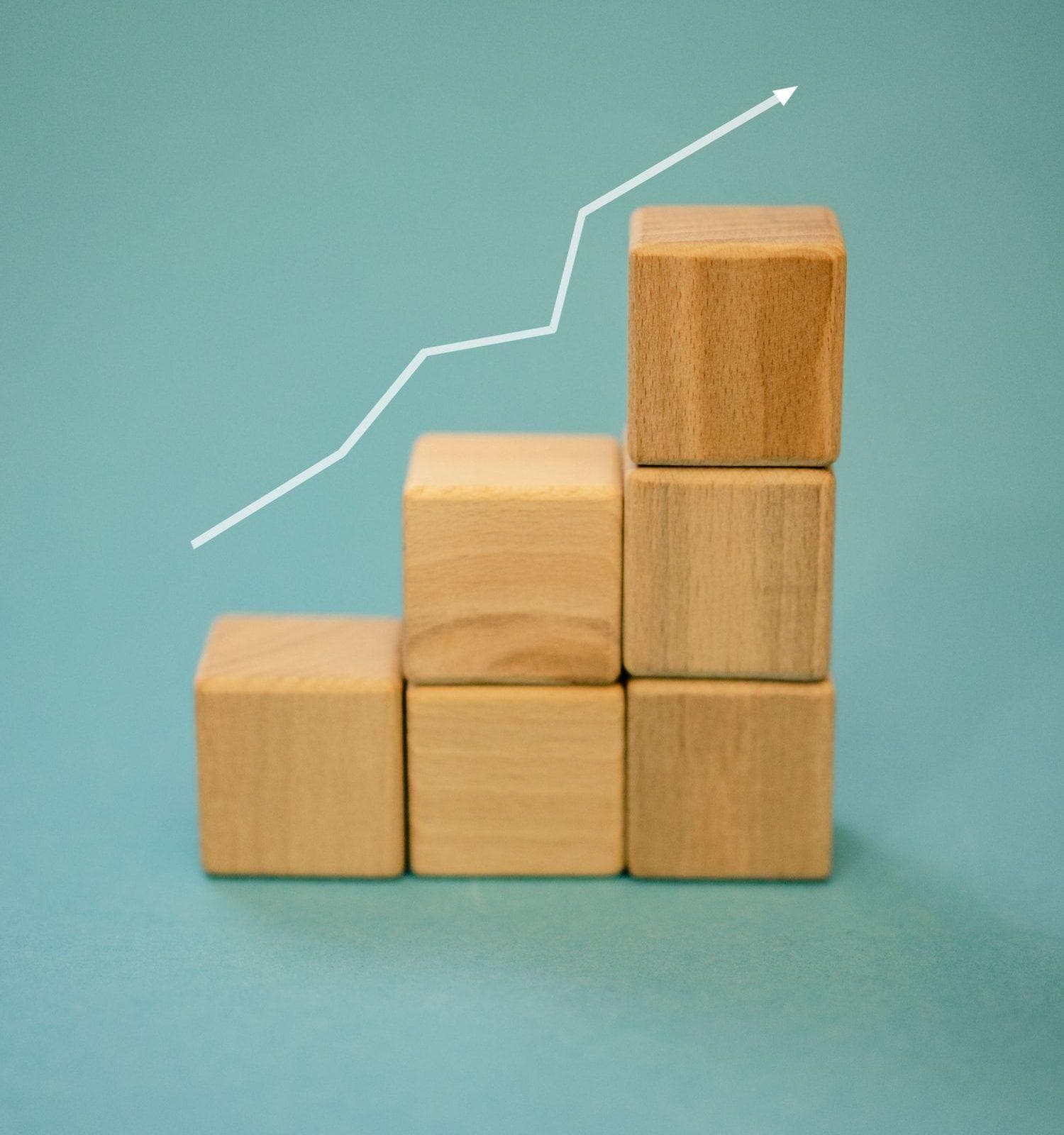 Wooden blocks stacked in ascending order with a rising growth arrow